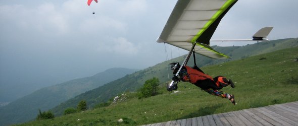 Hängegleiter Start Ein Hängegleiter startet von einer Holzrampe auf einem Berg